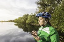 Jeune femme au lac textos sur smartphone, Augsbourg, Bavière, Allemagne — Photo de stock