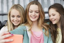 Três meninas posando para selfie smartphone no abrigo — Fotografia de Stock