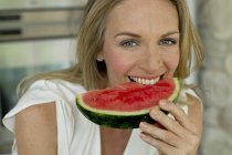 Reife Frau beißt Wassermelone und schaut in die Kamera — Stockfoto