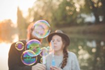 Jeune couple jouant avec des bulles — Photo de stock
