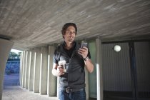 Hombre adulto medio mensajes de texto en el teléfono inteligente en la ciudad underpass - foto de stock