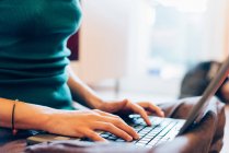 Cropped mid section of mid adult woman typing on laptop computer — Stock Photo