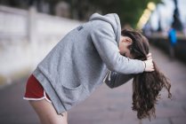 Young female runner tying up long hair on riverside — Stock Photo