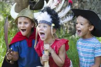 Three children wearing fancy dress costumes playing in park — Stock Photo