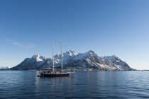 Navio navegando na frente de montanhas cobertas de neve — Fotografia de Stock