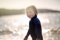 Niño con el pelo mojado usando traje de neopreno, retrato - foto de stock