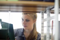Young female student searching for textbook in library — Stock Photo