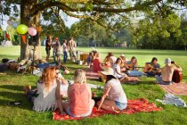 Grupo de amigos ouvindo música debaixo da árvore do parque na festa do pôr do sol — Fotografia de Stock