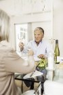 Coppia di anziani seduti insieme a tavola, tenendo bicchieri di vino, facendo toast — Foto stock