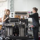 Две женщины работают с традиционным печатным станком в мастерской — стоковое фото