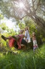 Low angle view of three girls playing on tree tire swing in garden — Stock Photo