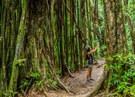 Jovem turista fotografa no smartphone na selva, Manoa Falls, Oahu, Havaí, EUA — Fotografia de Stock