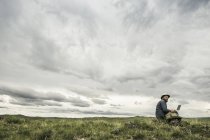 Escursionista di sesso maschile seduto su rocce con computer portatile guardando verso il paesaggio, Cody, Wyoming, Stati Uniti d'America — Foto stock
