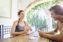 Femme mature et fils jouant aux cartes à la table de patio — Photo de stock
