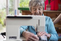 Старшая женщина с помощью швейной машинки — стоковое фото
