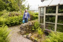 Reife Frau trägt Gießkanne im Garten — Stockfoto