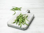 Fresh green beans on wooden chopping board — Stock Photo