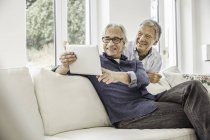 Двое мужчин дома, смотрят на цифровой планшет — стоковое фото