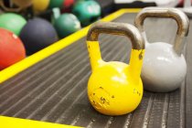Pesos de sinos de chaleira amarelos e cinzentos no ginásio — Fotografia de Stock