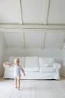 Retrato de bebê menina criança e apontando na sala de estar — Fotografia de Stock