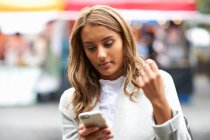 Молода жінка використовує смартфон, на відкритому повітрі — стокове фото