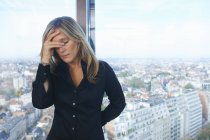 Donna d'affari stressata davanti alla finestra dell'ufficio con paesaggio urbano di Bruxelles, Belgio — Foto stock