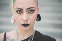 Portrait of young female punk with nose and earlobe piercings — Stock Photo