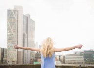 Young woman with arms outstretched, rear view — Stock Photo