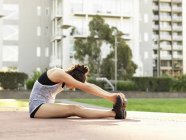 Young woman stretching in park — Stock Photo