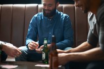 Three male friends playing cards in traditional UK pub — Stock Photo