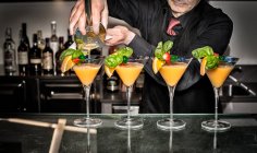Barman pouring cocktails, mid section — Stock Photo