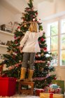 Girl decorating Christmas tree at home — Stock Photo