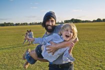 Mid adult man carrying son in field — Stock Photo
