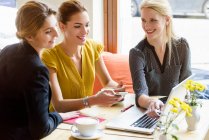 Drei junge Frauen schauen in Café auf Laptop — Stockfoto