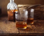 Verres et bouteille de whisky sur table en bois — Photo de stock