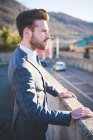 Stylish young man looking out from roadside wall — Stock Photo