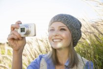 Молода жінка фотографує з фотоапаратом у полі — стокове фото