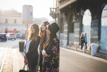 Three young women standing on city street — Stock Photo