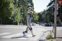 Vater trägt Kleinkind-Sohn über Zebrastreifen — Stockfoto