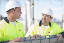 Builder and site manager using spirit level on construction site wall — Stock Photo