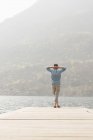Rear view of young man looking out from pier, Lake Mergozzo, Verbania, Piemonte, Italy — Stock Photo