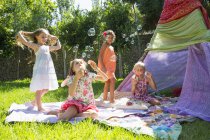 Girls blowing bubbles in summer garden party — Stock Photo