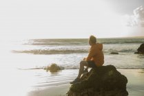 Reifer Mann sitzt auf einem Felsen und blickt aufs Meer — Stockfoto