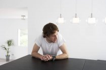 Pensive young man sitting at dining room table — Stock Photo