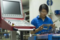 Jeune femme tenant des appareils de mesure dans un atelier industriel — Photo de stock