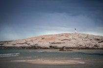 Distant view of young woman strolling on rock formation at coast, Costa Rei, Sardinia, Italy — Stock Photo