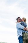 Vista basso angolo di coppia romantica abbracciare e baciare contro il cielo — Foto stock