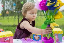 Criança feminina com flores de papel na festa de aniversário no jardim — Fotografia de Stock