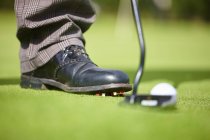 Vista recortada del pie del golfista que usa zapato de golf, club de golf y pelota de golf - foto de stock