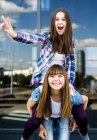 Two young women making peace sign and piggybacking — Stock Photo